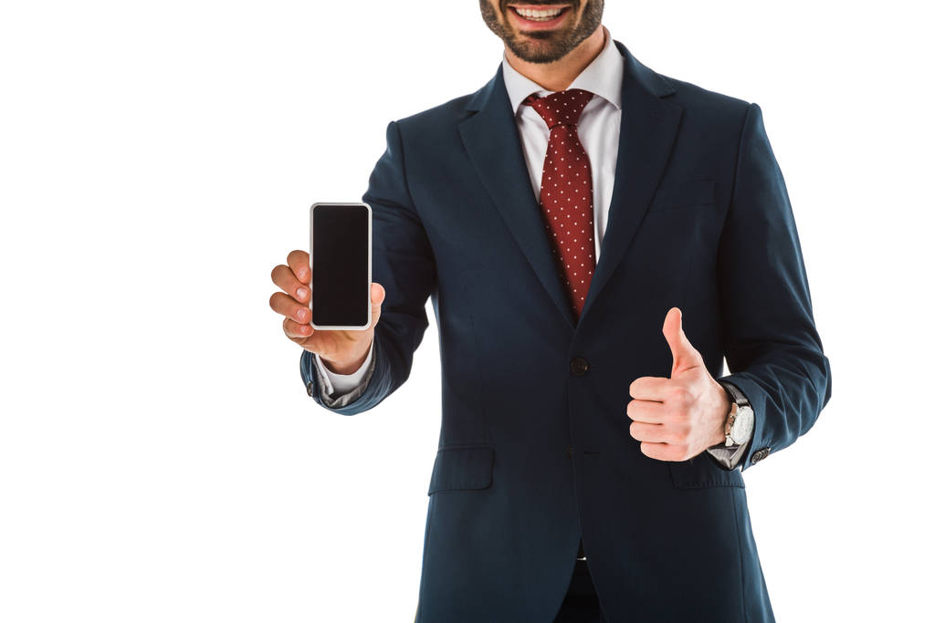 oříznutý pohled obchodníka zobrazující palce nahoru při současném přidržovaní telefonu Smartphone s prázdnou obrazovkou izolovanou na bílém - Fotografie, Obrázek