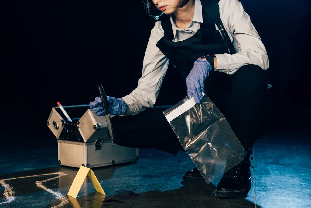 Ausgeschnittener Blick auf Ermittler mit Messer und Reißverschlusstasche am Tatort - Foto, Bild