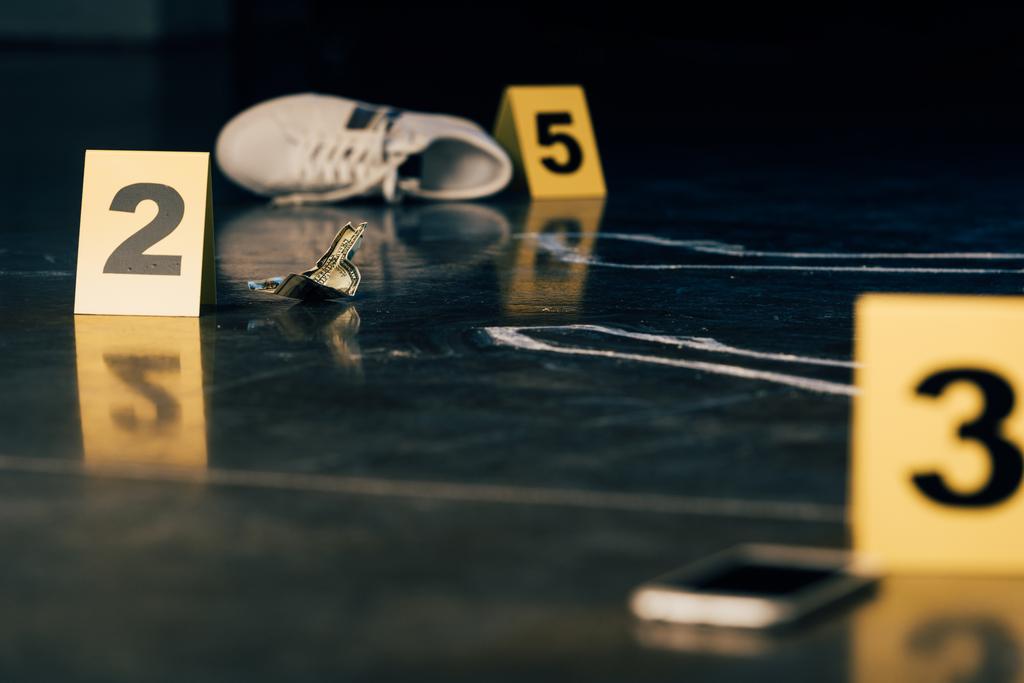 犯罪現場でのスマートフォン、チョークの輪郭、靴、ドル紙幣、証拠マーカーの選択的な焦点 - 写真・画像
