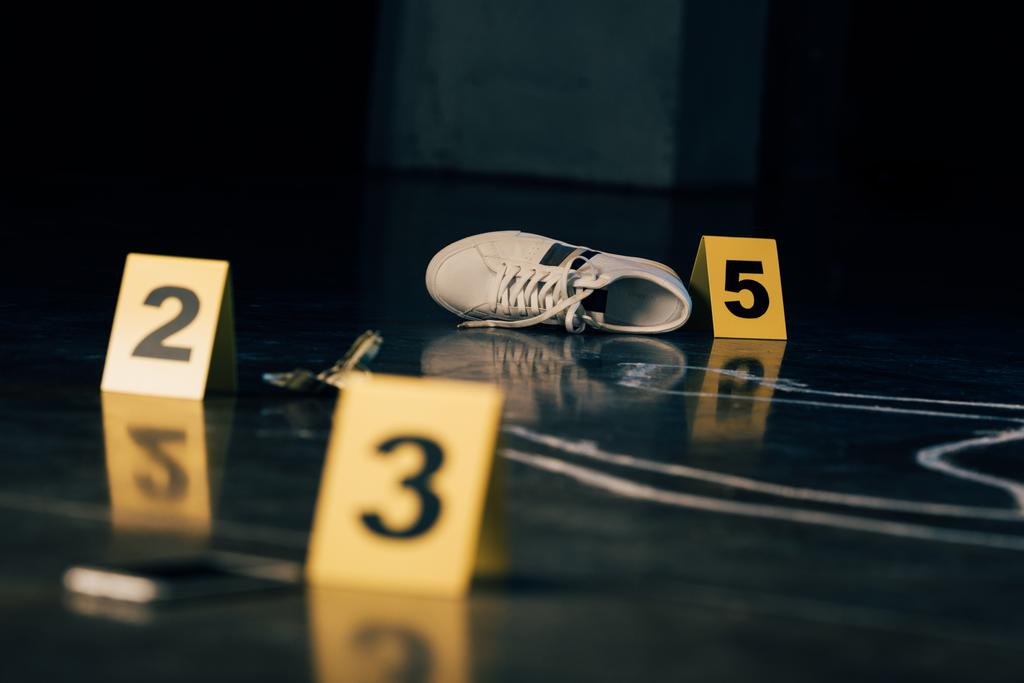 犯罪現場における靴、ドル紙幣、チョークの輪郭と証拠マーカーの選択的な焦点 - 写真・画像