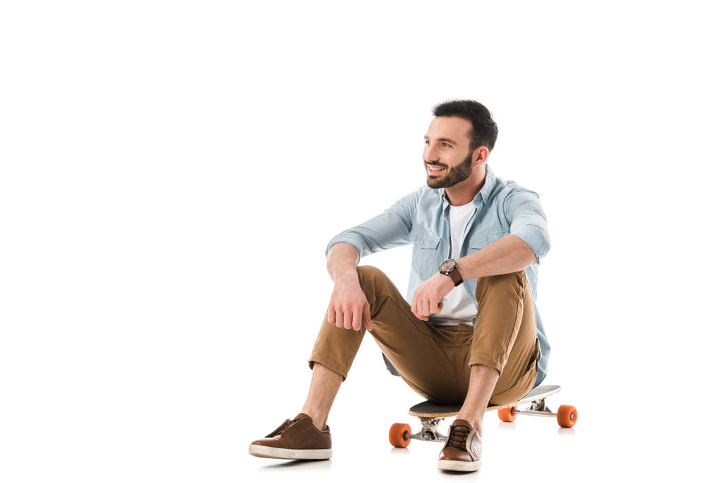 gelukkige man zittend op Longboard en kijken weg geïsoleerd op wit - Foto, afbeelding