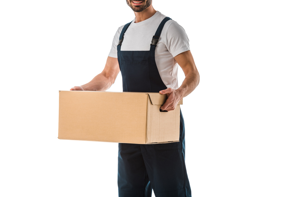 обрізаний вид доставки людини в комбінезоні, що тримає картонну коробку ізольовано на білому
 - Фото, зображення