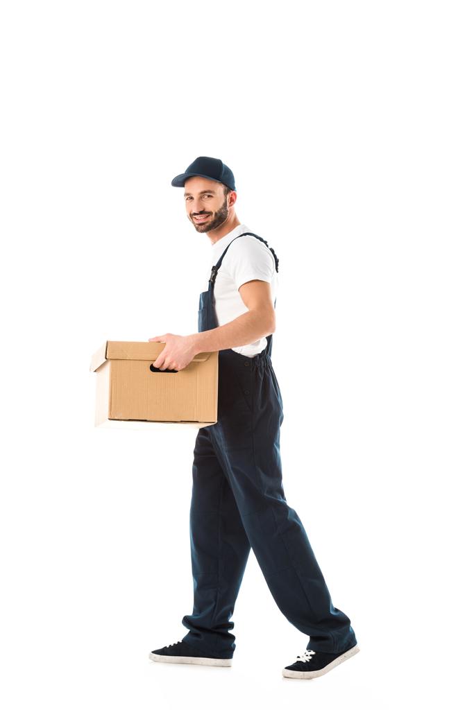 handsome smiling delivery man carrying cardboard box and looking at camera isolated on white - Photo, Image