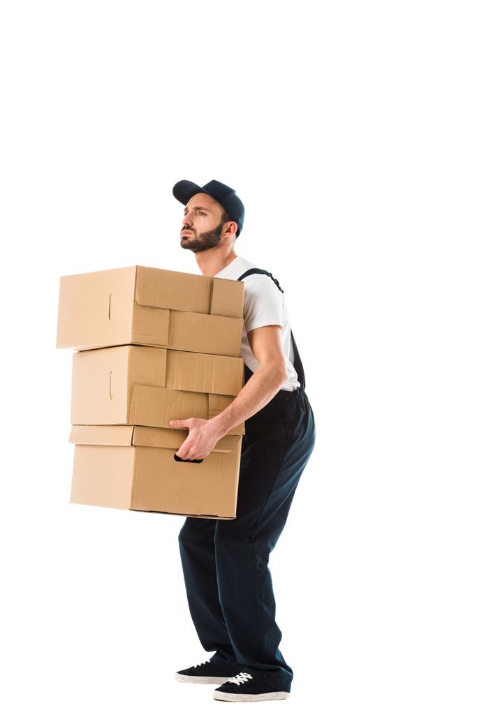 knappe serieuze delivery man vervoert kartonnen dozen geïsoleerd op wit - Foto, afbeelding
