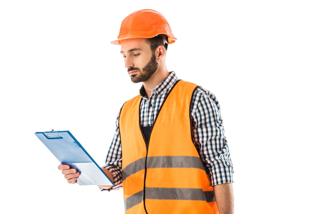 vážný stavební pracovník v ochranné vestě a helmici s pohledem na schránku izolovaný na bílém - Fotografie, Obrázek
