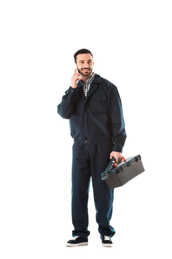 operaio sorridente in tuta da lavoro che parla su smartphone e tiene la cassetta degli attrezzi isolata su bianco
 - Foto, immagini