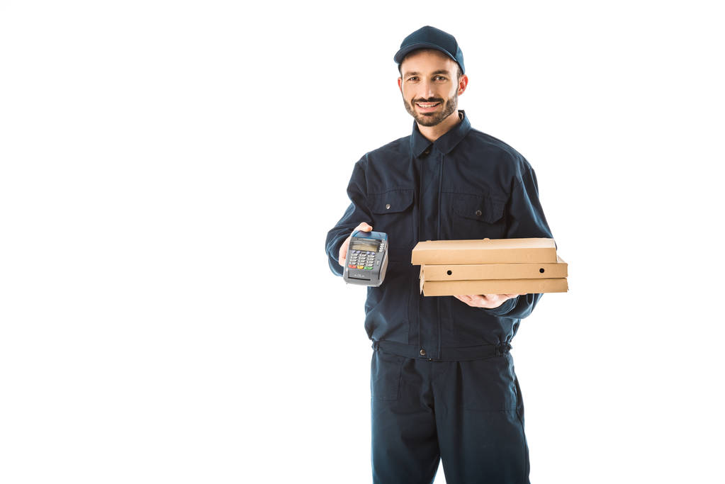 Lächeln Kurier in Overalls mit Zahlungsterminal und Pizzakartons isoliert auf weiß - Foto, Bild