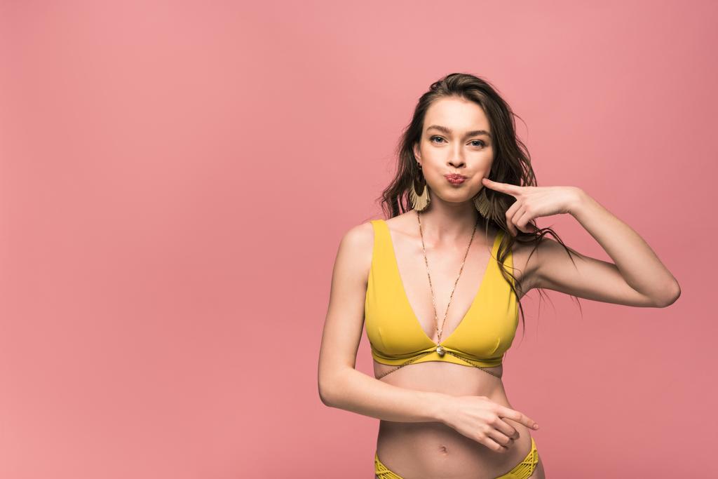 front view of pretty young woman in yellow swimsuit isolated on pink - Photo, Image