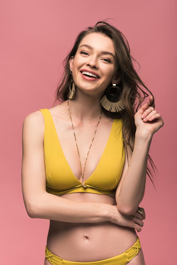 krásná mladá žena ve žlutém plavkách, usmívající se izolovaně na růžovém - Fotografie, Obrázek