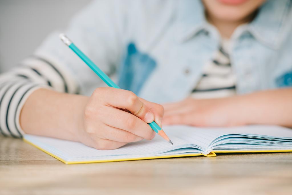 частковий погляд на шкільного малюка, що пише в копіювальній книзі під час виконання домашнього завдання
 - Фото, зображення