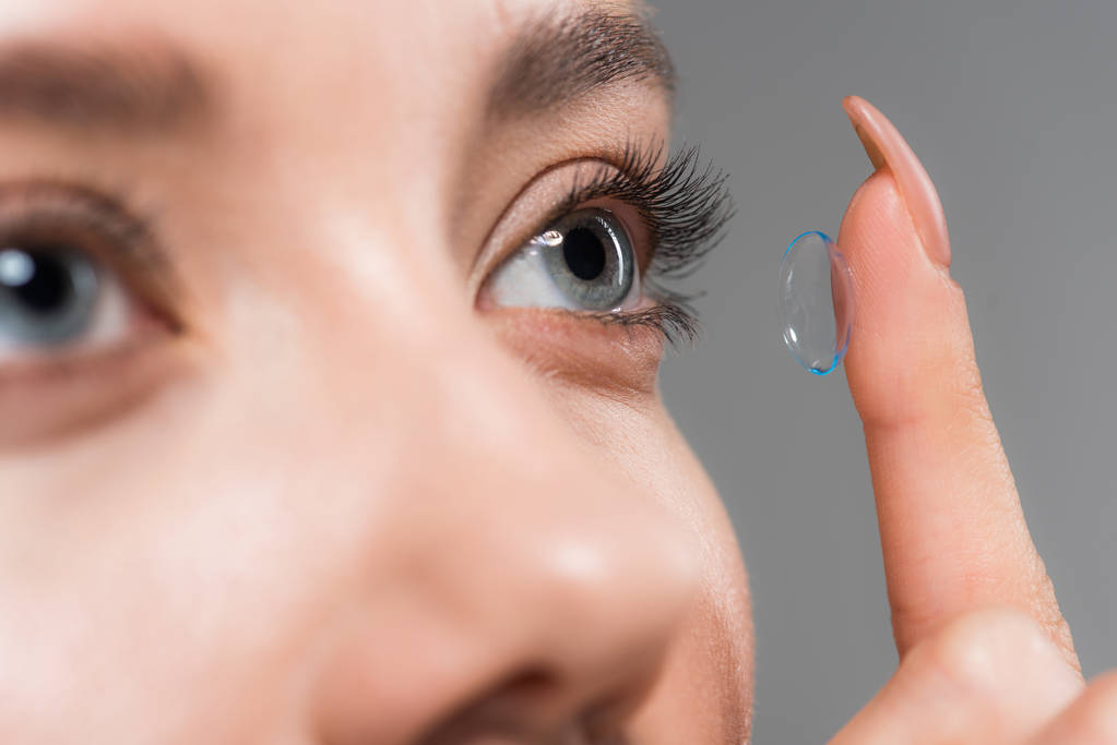 oříznutý pohled mladé ženy připevňování kontaktní čočky izolované na šedé - Fotografie, Obrázek