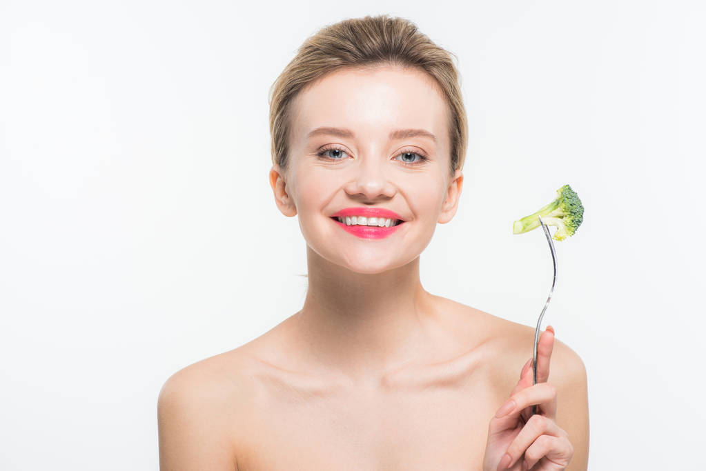 cheerful naked woman holding fork with green ripe broccoli isolated on white   - Photo, Image