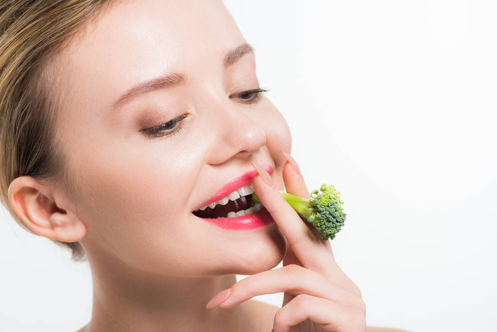 vonzó és boldog nő étkezési zöld érett brokkoli izolált fehér    - Fotó, kép