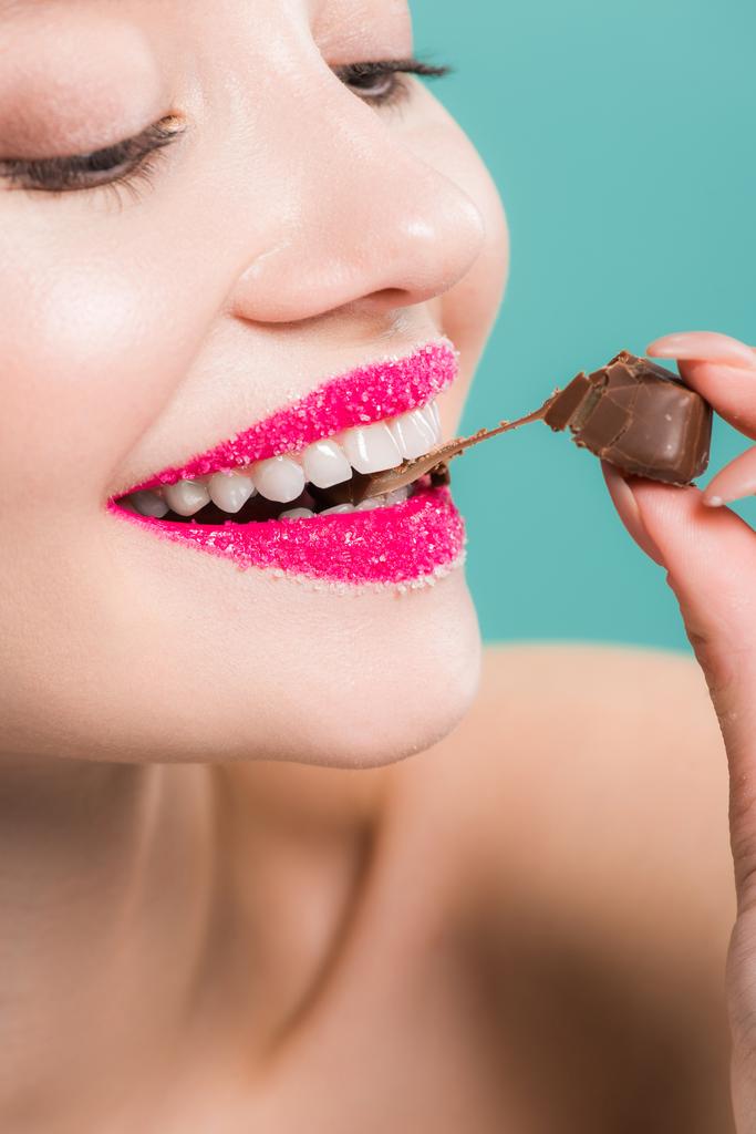 przycięte widok wesoły kobieta jedzenie cukierki czekolada na białym tle niebieski   - Zdjęcie, obraz