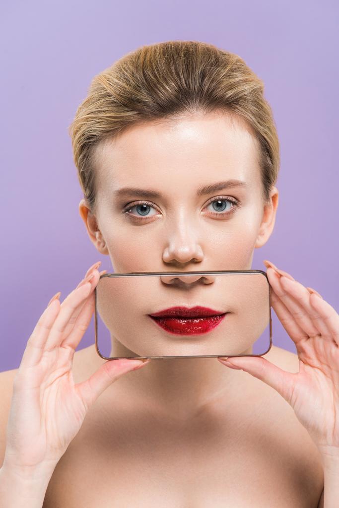 attrayant nu femme couvrant la bouche avec smartphone avec des lèvres sur l'écran isolé sur violet
   - Photo, image