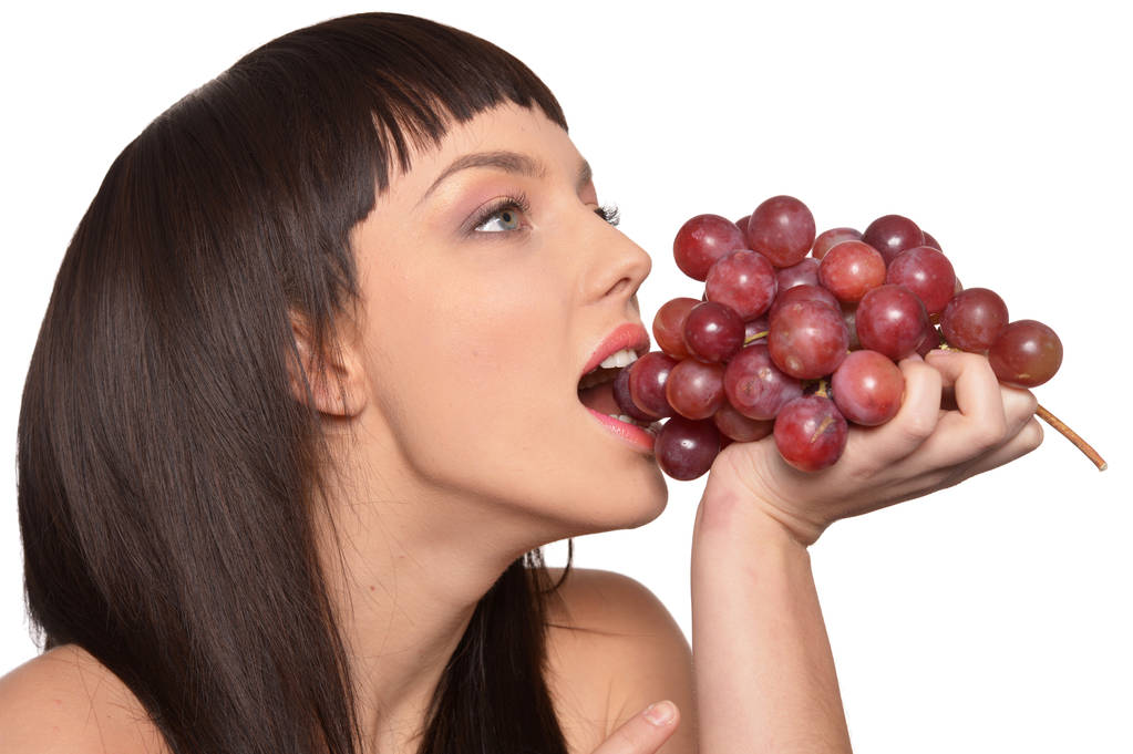 Retrato de una joven posando con uvas aisladas sobre fondo blanco
 - Foto, imagen
