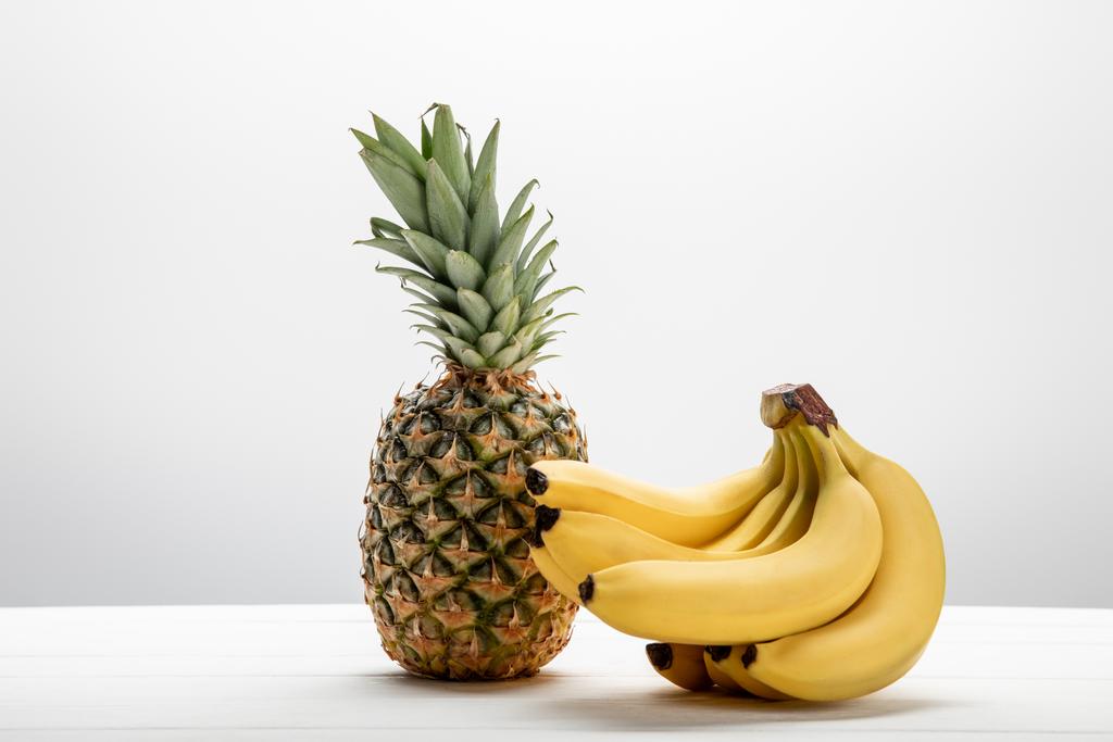 zralé žluté banány v blízkosti sladkého a chutného ananasu na bílém  - Fotografie, Obrázek