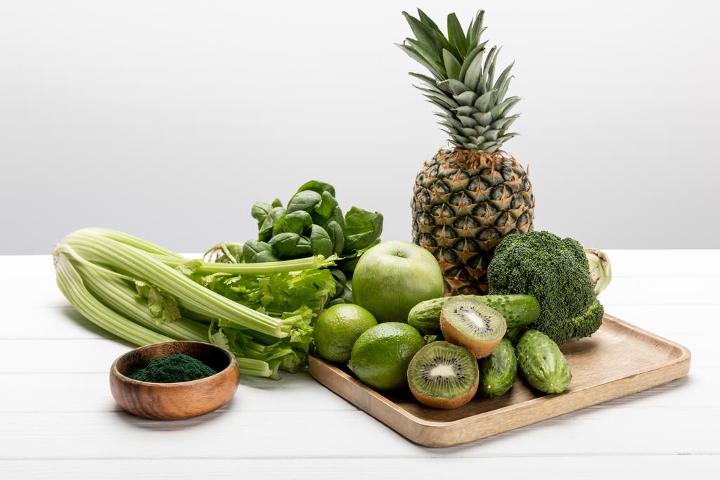sabrosa piña, manzana y limas cerca de verduras orgánicas y crudas en blanco
  - Foto, imagen