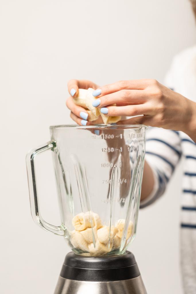 vue recadrée de femme mettant des bananes sucrées mûres dans le mélangeur sur blanc
  - Photo, image