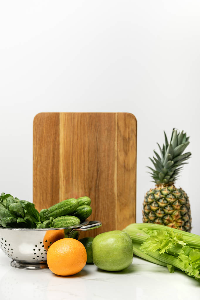 fruits mûrs près de légumes frais et planche à découper en bois sur blanc
  - Photo, image