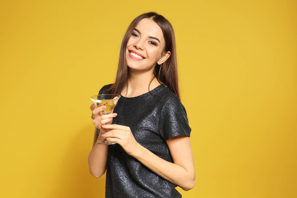 Красивая молодая женщина со стаканом коктейля мартини на цветном фоне
 - Фото, изображение