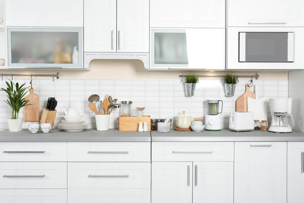 Diferentes aparelhos, pratos limpos e utensílios no balcão da cozinha
 - Foto, Imagem