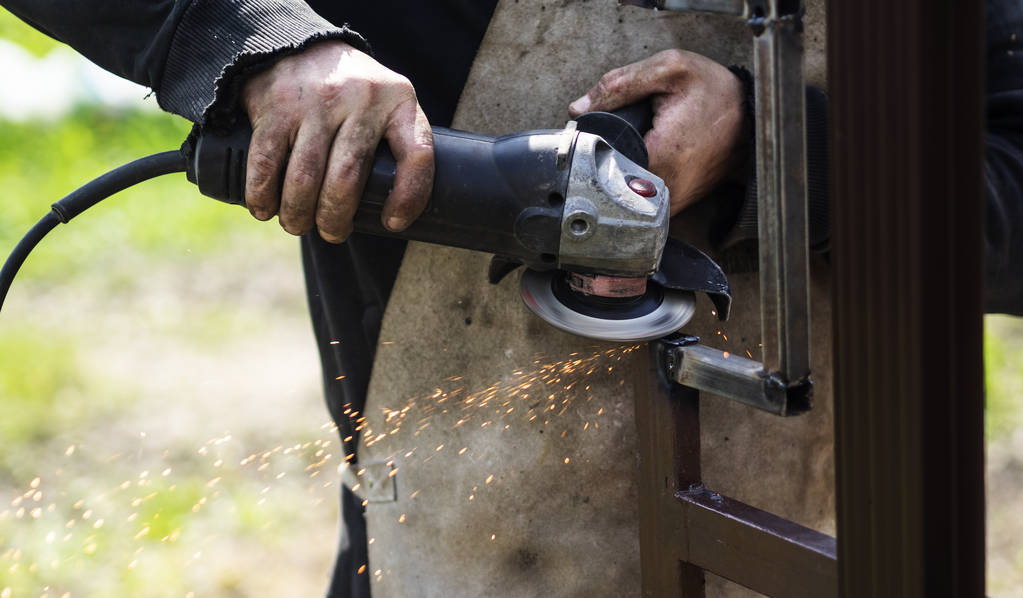 Руки металевого працівника з використанням болгарки
 - Фото, зображення