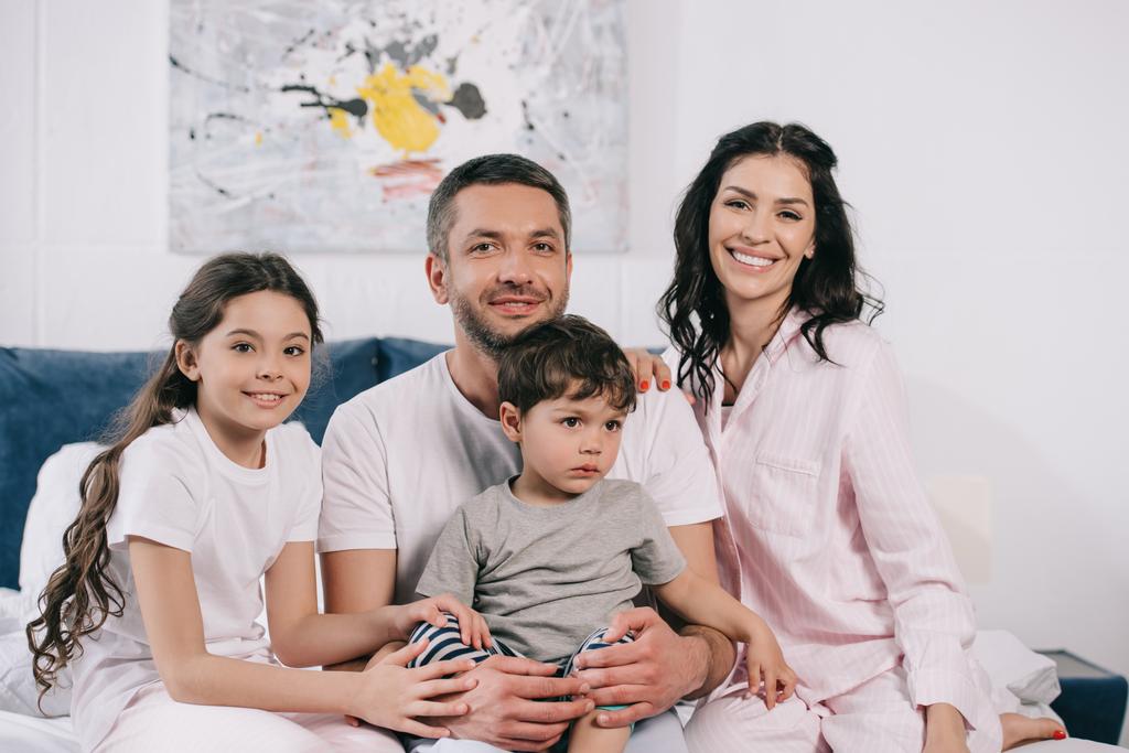 cheerful parents smiling near happy cute kids in bedroom  - Photo, Image