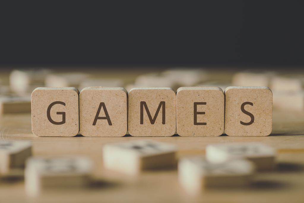 黒で隔離された木製の表面に文字を持つブロックで囲まれた単語ゲームを持つキューブの選択的な焦点 - 写真・画像