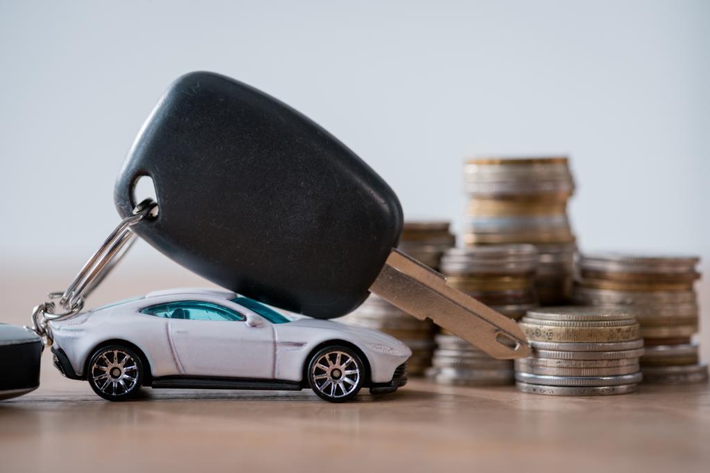 мініатюрний автомобіль, ключі від автомобілів і металеві монети на дерев'яній поверхні ізольовані на сірому
 - Фото, зображення