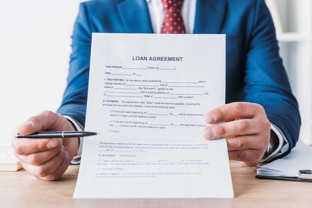 visão parcial do empresário apontando com caneta no contrato de empréstimo
 - Foto, Imagem