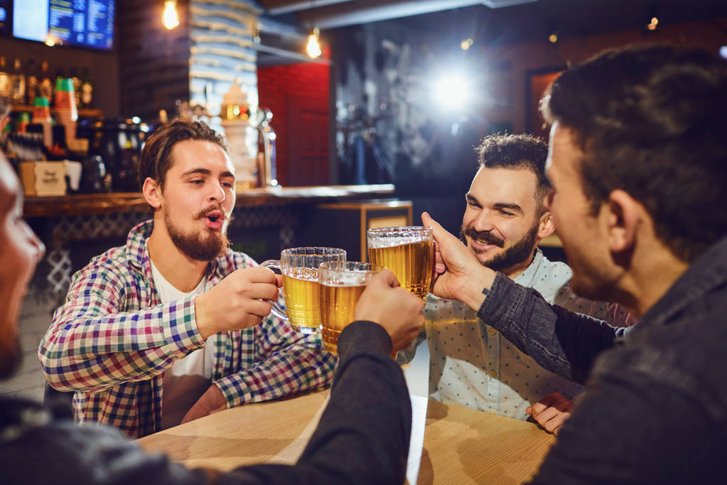 Друзья разговаривают, пьют пиво в баре
. - Фото, изображение