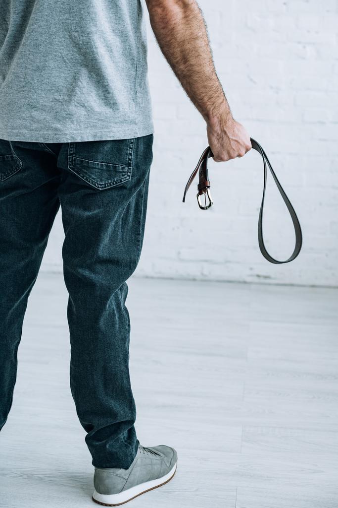 cropped view of man holding leather belt at home - Photo, Image