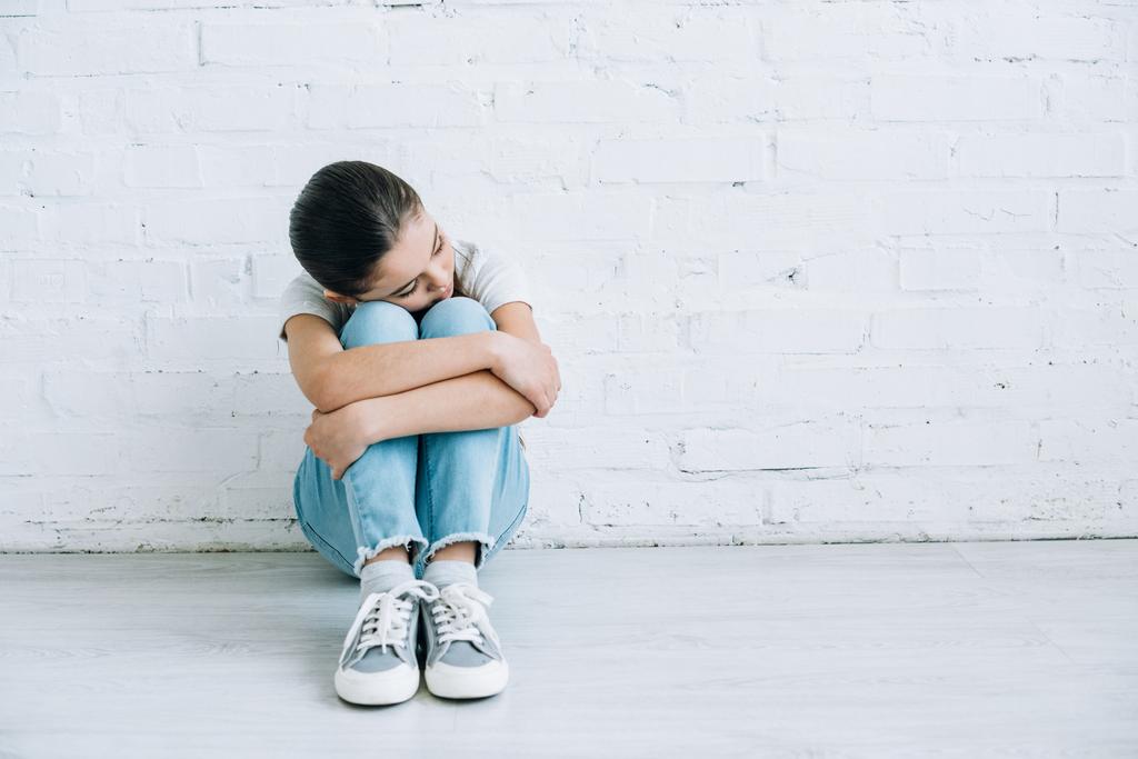 niño preadolescente molesto sentado en el suelo en casa
 - Foto, imagen