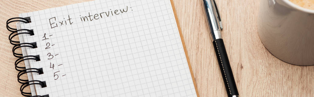 Panoramaaufnahme eines Notizbuchs mit Ausgangs-Interview-Schriftzug und Zahlen auf Holztisch in der Nähe von Stift und Kaffeetasse - Foto, Bild