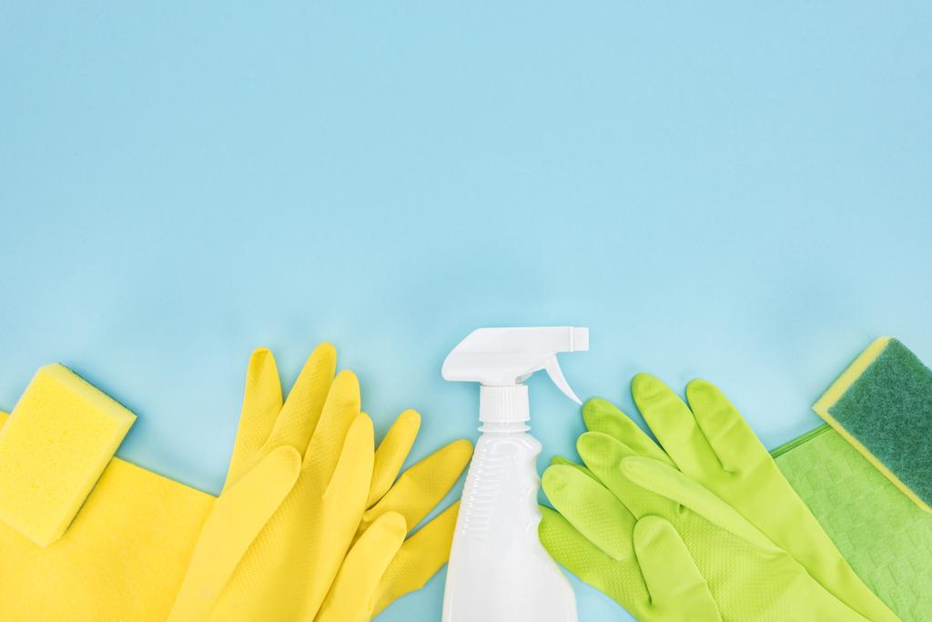 vista superior de guantes de goma amarillos y verdes, esponjas, trapos y botella de spray con detergente sobre fondo azul con espacio para copiar
 - Foto, imagen