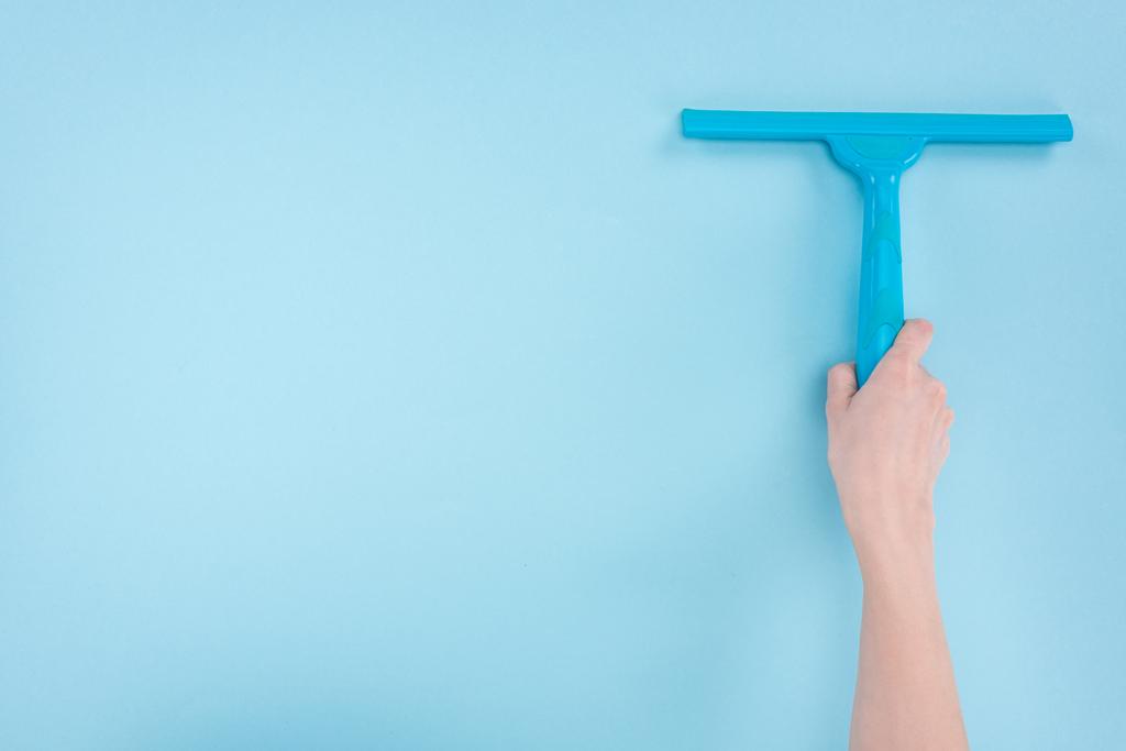 cropped view of woman holding squeegee on blue background - Photo, Image