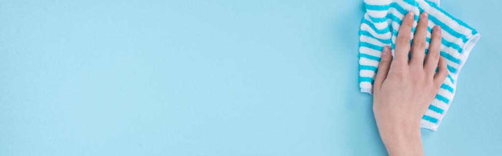 plano panorámico de mujer sosteniendo trapo rayado sobre fondo azul
 - Foto, Imagen