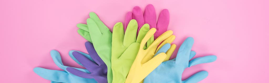 panoramic shot of multicolored rubber gloves in pile on pink background - Photo, Image