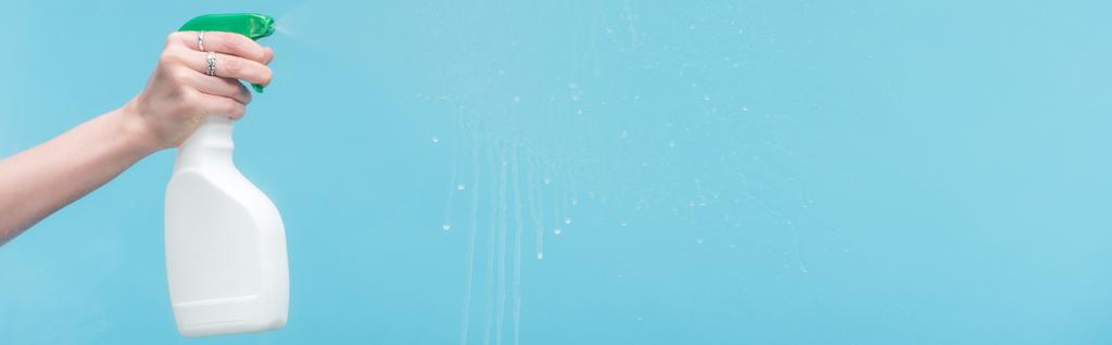 panoramic shot of woman spraying glass with detergent on blue background - Photo, Image