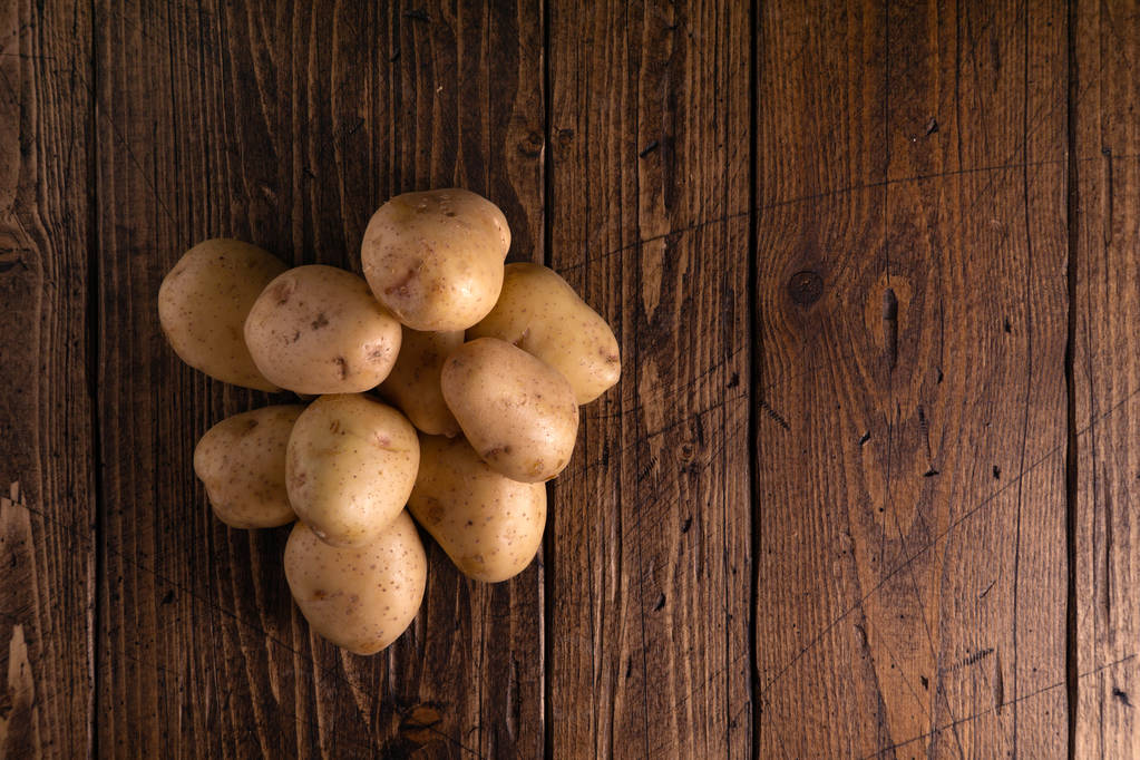 Rustik ahşap yüzeyde taze patates yığını. Organik gıda, karbonhidrat, yumru. - Fotoğraf, Görsel