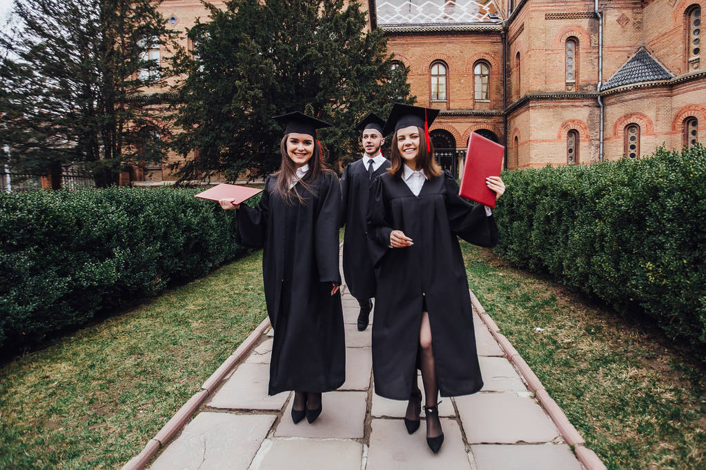 Successful graduates with diplomas walking in university garden - Photo, Image