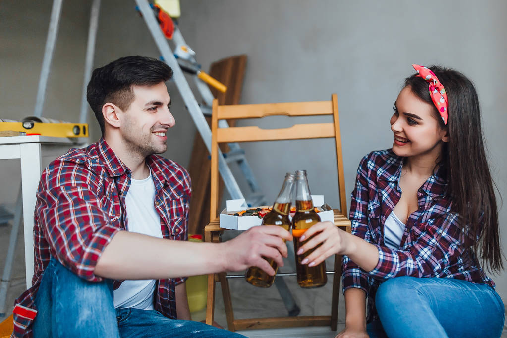 Mann hält Schachtel mit Pizza und Frau sitzt daneben und trinkt Bier - Foto, Bild
