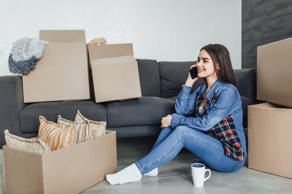 Женщина делает онлайн покупки, сидит на полу в новом доме
 - Фото, изображение