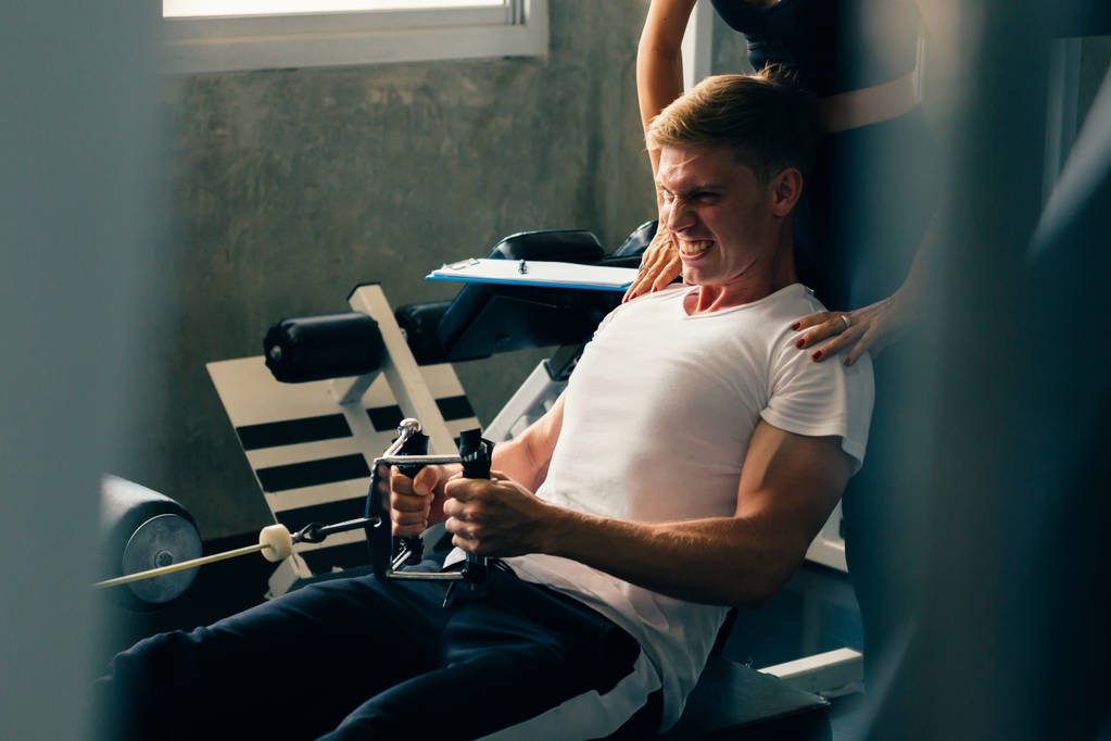 Νεαρός Καυκάσιος σε γυμναστήριο, προπονείται σκληρά και τραβάει βάρη σε καθιστή καλωδιοταινία - Φωτογραφία, εικόνα