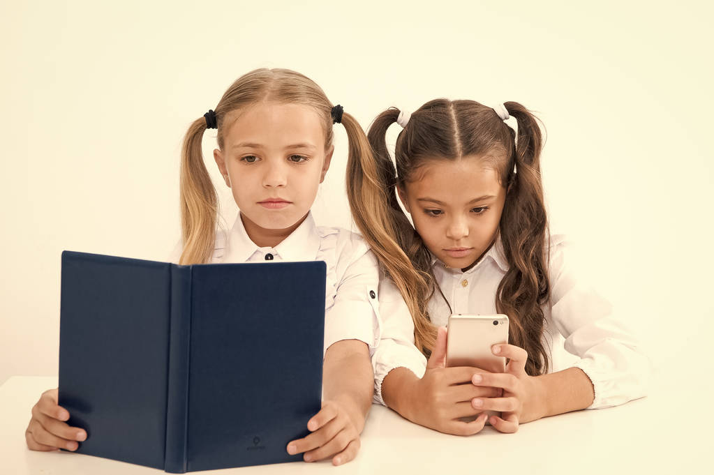 Concetto di lettura. Ottenere informazioni. Bambine che leggono libri di carta e ebook in smartphone. La scelta giusta - Foto, immagini