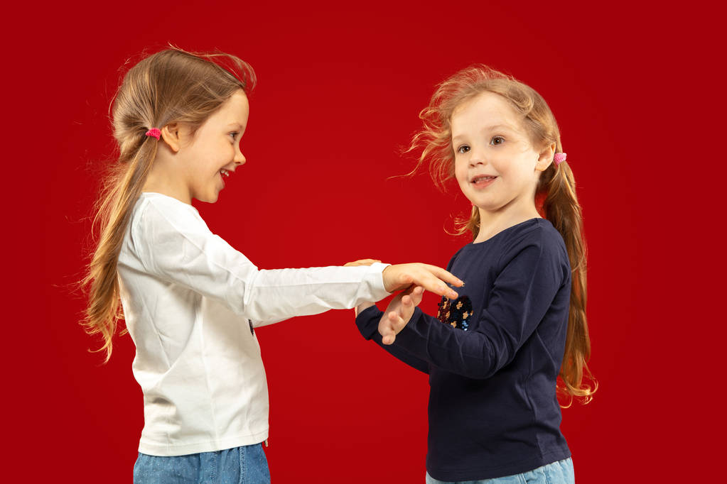 Kaunis emotionaalinen pikkutytöt eristetty punaisella taustalla
 - Valokuva, kuva