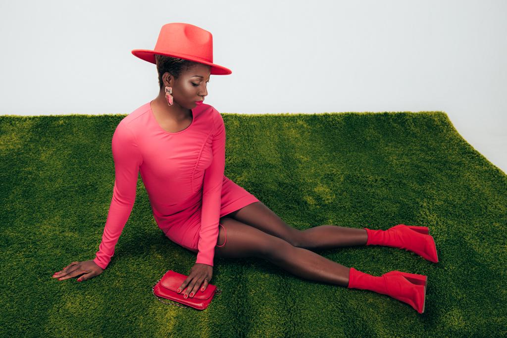 african american woman in pink dress and hat posing with bag on green grass - Photo, Image