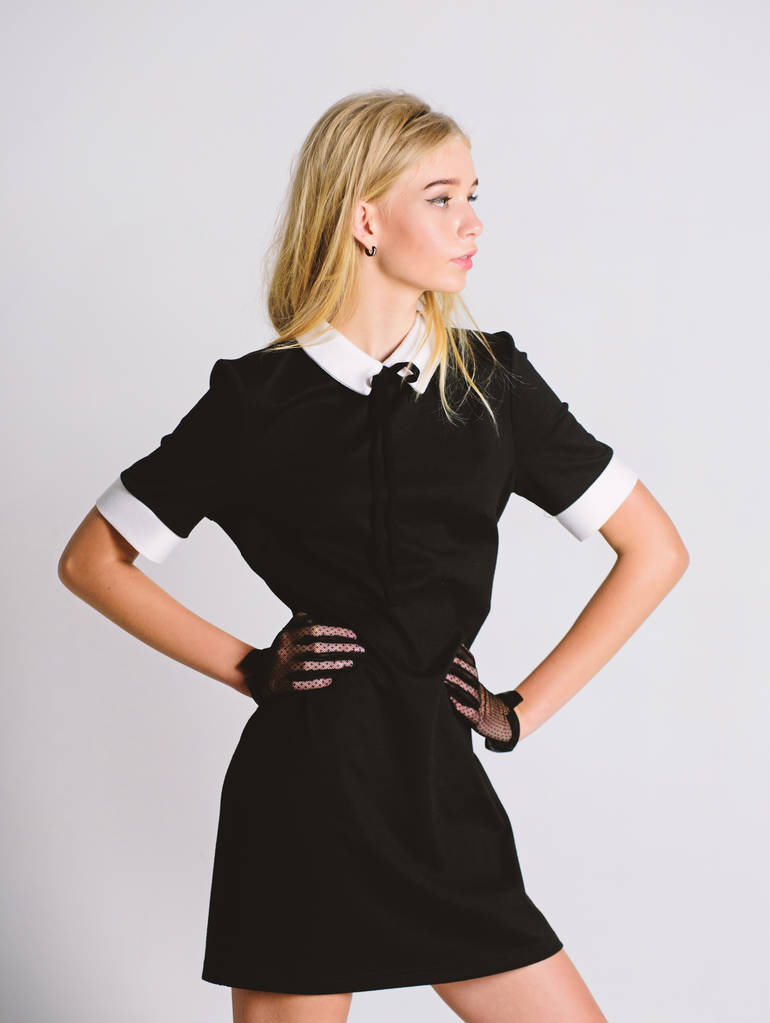 Ξανθιά κοπέλα φορούν κομψό μαύρο φόρεμα. Τυπική ομοιόμορφη ελίτ σχολείο, κολέγιο ή υπηρέτρια. Ρετρό μοντέλο. Κομψότητα συναντά την απλότητα. Μοντέρνα στολή. Vintage και ρετρό στυλ. Η έννοια vintage μόδα - Φωτογραφία, εικόνα