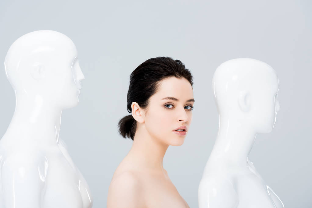 gyönyörű lány közelében fehér mannequins nézett kamera izolált szürke - Fotó, kép